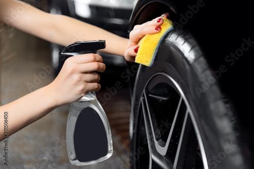Car wash service, detailing using spray and sponge to wipe black tire © Parilov