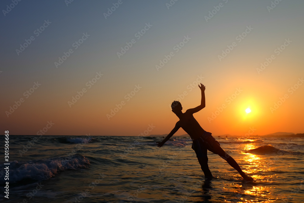 A silhouette of a person relaxing on the sea.Happiness after completion of work.sunset and sunrise.