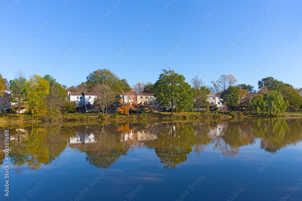 Suburban neighborhood of Falls Church in autumn near water in Virginia, USA. Colorful landscape with deciduous trees in fall.