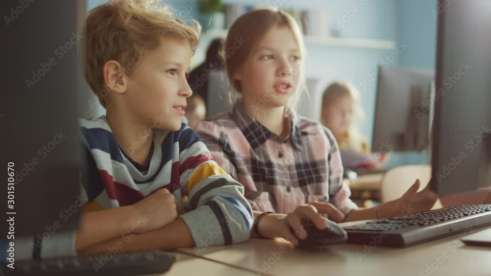 Elementary School Computer Science Classroom: Portrait of Smart Girl and Boy Talking while using Personal Computer, Learning Informatics, Internet Safety, Programming Language for Software Coding Elementary School Computer Science Classroom: Portrait of Smart Girl and Boy Talking while using Personal Computer, Learning Informatics, Internet Safety, Programming Language for Software Coding