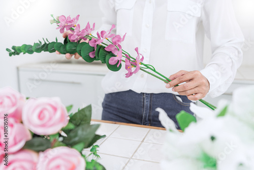 young women business owner florist making or Arranging Artificial flowers vest in her shop, craft and hand made concept