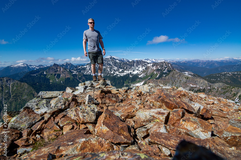Fototapeta premium Adventurous man standing on top of a mountain.