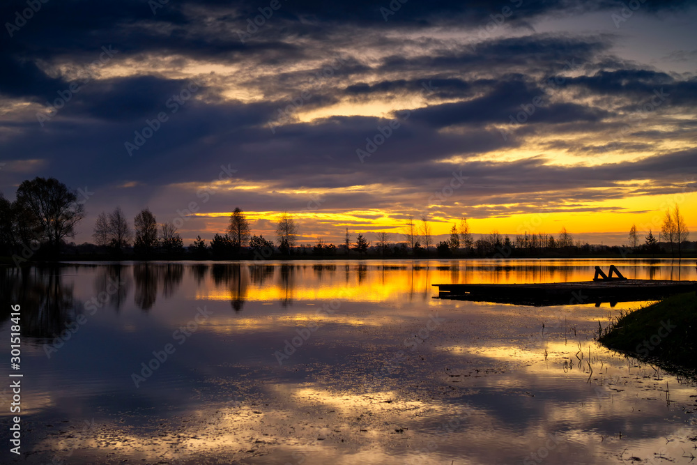 Tranquil lake reflecting a vivid orange sunset
