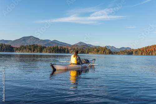 Wilderness woman enjoying the view of the Adirondacks from her white kayak