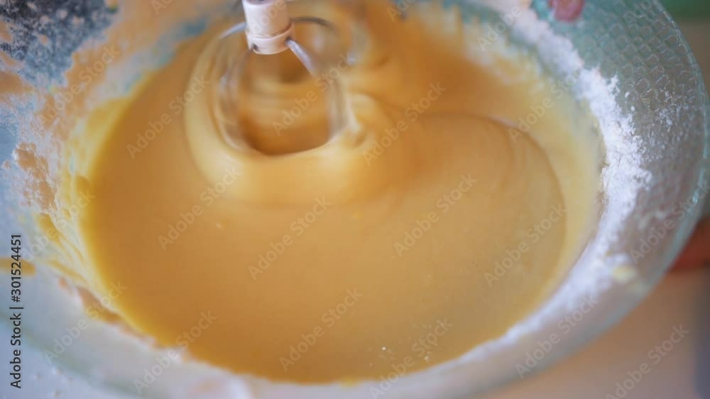 Kneading the muffin dough with an electric mixer in a transparent bowl. Homemade baking. Cooking in the kitchen. Mixing the dough for a pie, biscuit with a mixer, slow-motion shooting. Kneading the muffin dough with an electric mixer in a transparent bowl. Homemade baking. Cooking in the kitchen. Mixing the dough for a pie, biscuit with a mixer, slow-motion shooting.