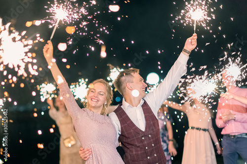 Beautiful wedding finale, the bride and groom and their guests lit sparklers in the street