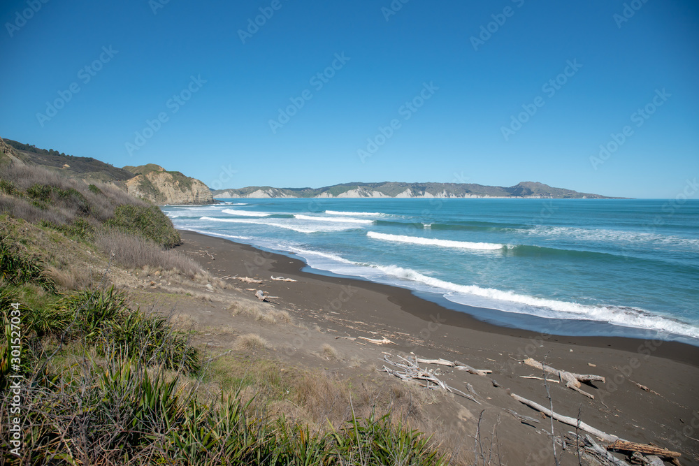 surf waves rolling in at the deserted empty coastal beach in Gisborne New Zealand