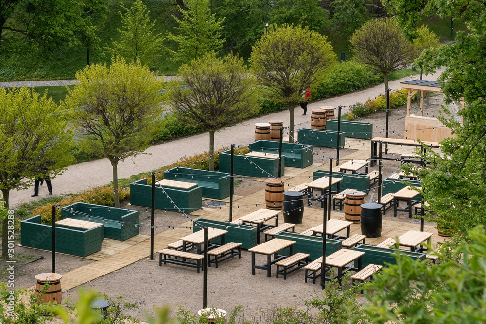 Wooden stylish pub located on public park, among greenery.