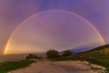 View of wonderful rainbow at sunrise on rainy day in the italian mountain