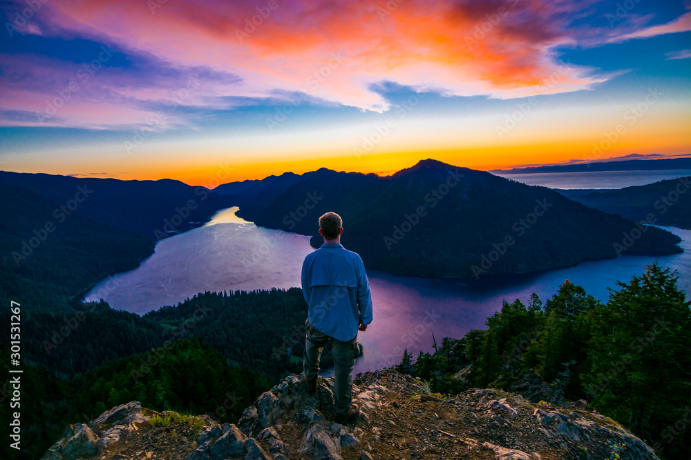 Adventurous man watching a sunset from a mountaintop.