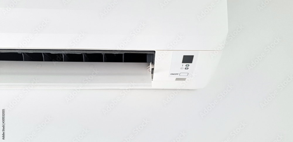 Modern air condition unit on a white wall inside the living room. Modern air condition unit on a white wall inside the living room.