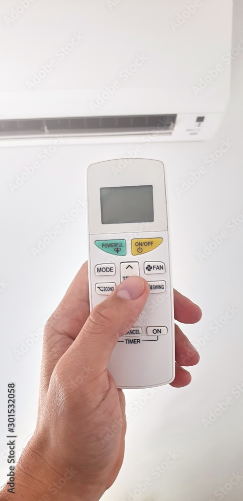 Modern airconditioner unit with a hand holding a remote. Modern airconditioner unit with a hand holding a remote.