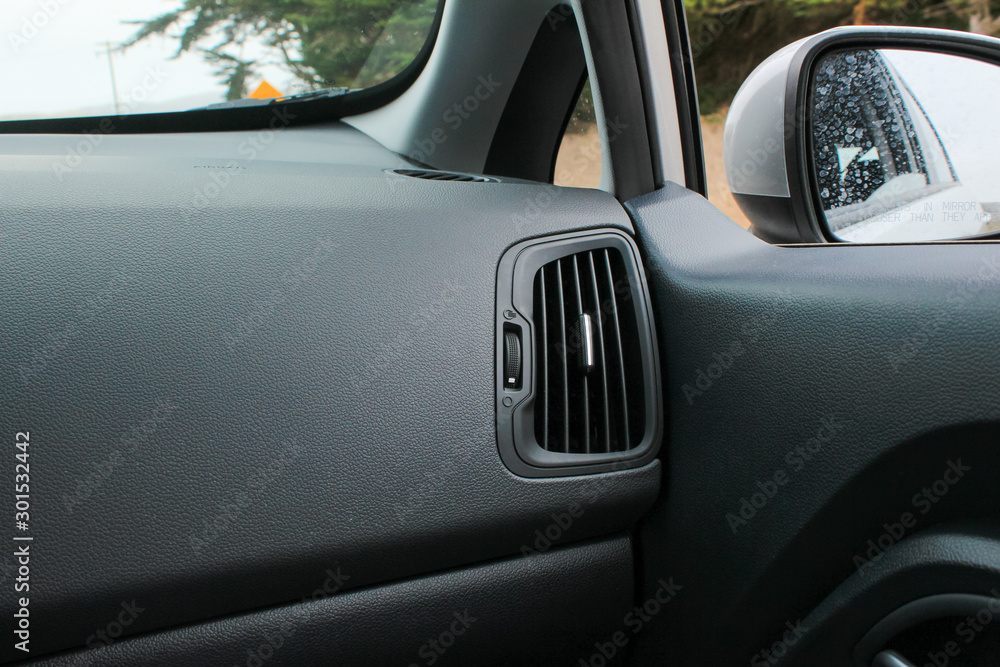 Car interior with view of air conditioner vent and side view mirror. ac vent for air flow in passenger side.