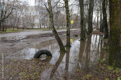 Large autumn rain pool near asphalt street in autumn