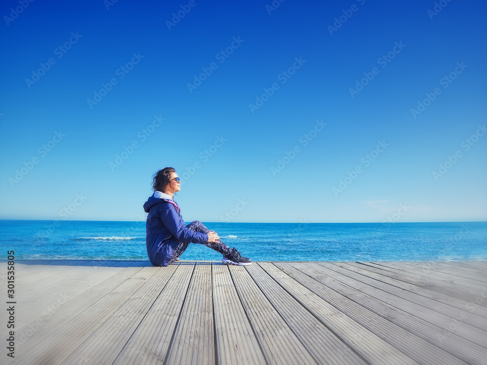 Woman on a wooden pier. Sea and sky background.