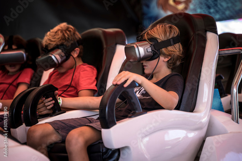 Photographie 8 years old boys wearing virtual reality headset, having fun in a VR amusement