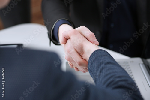 Two businessman shake hands as hello in office closeup