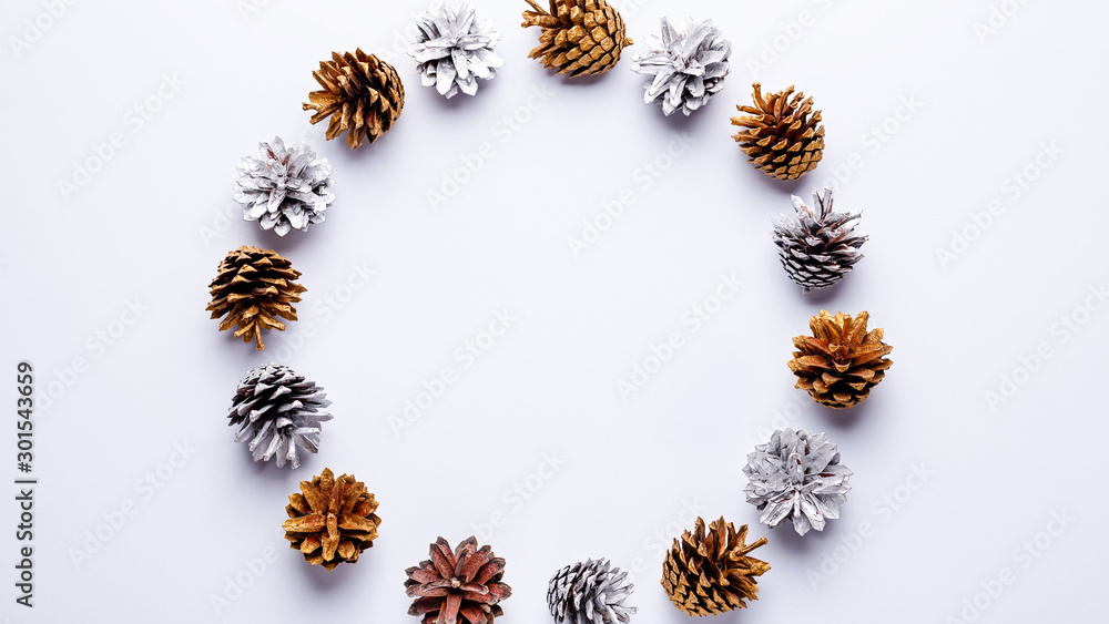 Painted pine cones frame on light grey background, Christmas golden and silver decorations flat lay, copy space, top view
