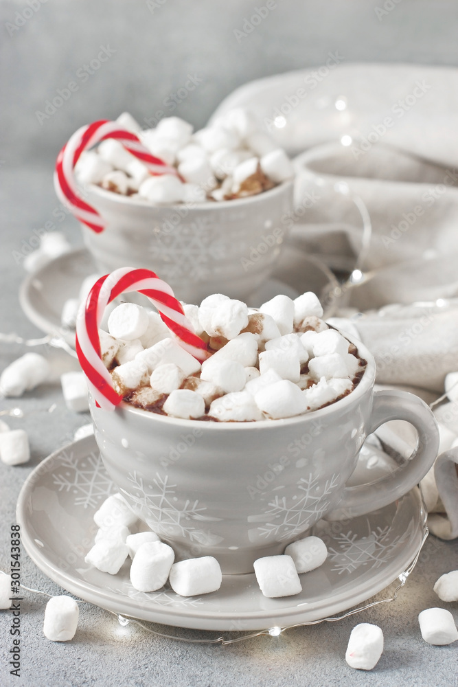 Gray mugs filled with hot chocolate and marshmallows decored candy cane Gray mugs filled with hot chocolate and marshmallows decored candy cane