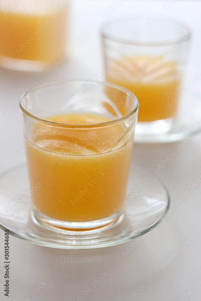 Two glasses of refreshing orange juice on a white table Two glasses of refreshing orange juice on a white table
