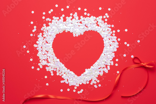Flat lay of pastel pink heart shaped confetti on red background. Love concept. Holiday celebration Valentine's Day. Wedding party decoration.