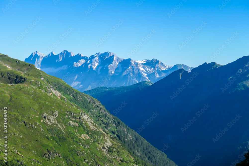 Massive mountain range of Schladming Alps, Austria. The slopes of Alps are steep, partially overgrown with green bushes. Dangerous mountain climbing.Clear and beautiful day. Endless mountain ranges,