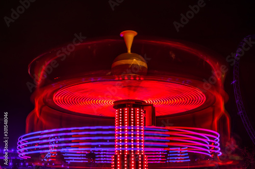 A blurry colorful carousel in motion at the amusement park, night illumination. Long exposure. photo