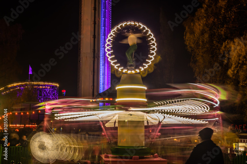 A blurry colorful carousel in motion at the amusement park, night illumination. Long exposure. photo