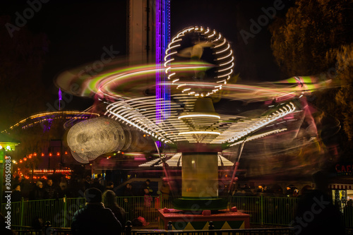 A blurry colorful carousel in motion at the amusement park, night illumination. Long exposure. photo