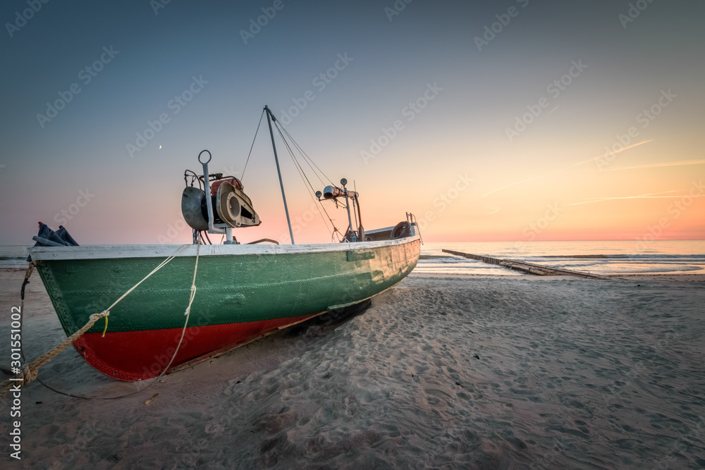 Old abandoned fishing boat at Latvia beach at sunset with colorful sky