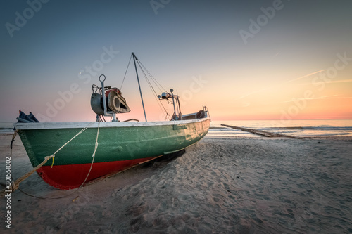 Old abandoned fishing boat at Latvia beach at sunset with colorful sky