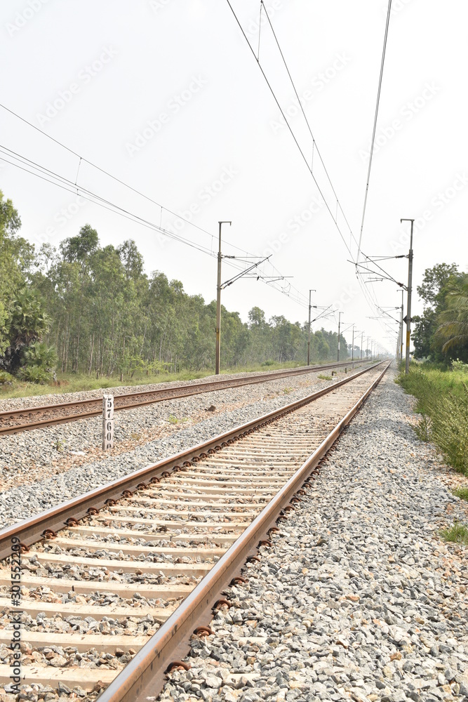 railway track with the background of sky, and green trees on both sides of the track. railway track with the background of sky, and green trees on both sides of the track.