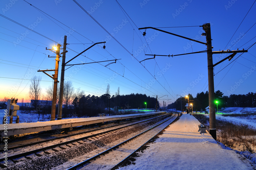 Evening winter landscape of the railway with burning semaphores and lanterns. The concept of a long road and countryside. Travel out of town concept