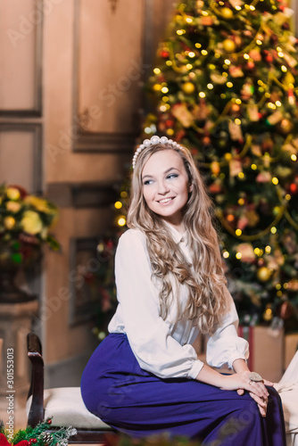 portrait of beautiful young blonde girl on background merry Christmas happy new year tree lights with star gift decor