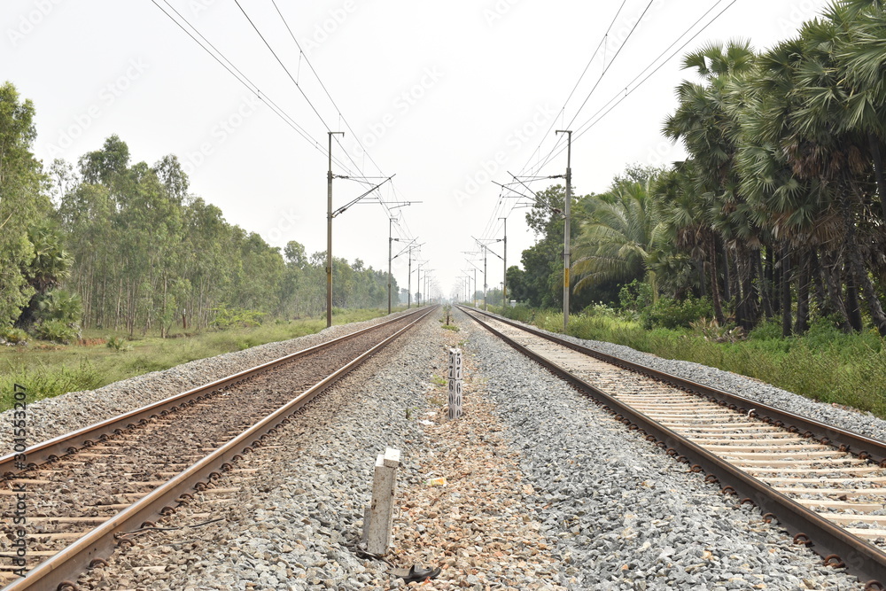 railway track with the background of sky, and green trees on both sides of the track. railway track with the background of sky, and green trees on both sides of the track.