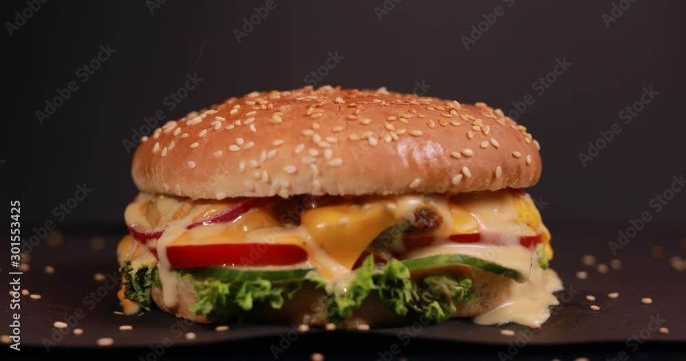 Making burger, sprinkle sesame seeds, black background Making burger, sprinkle sesame seeds, black background