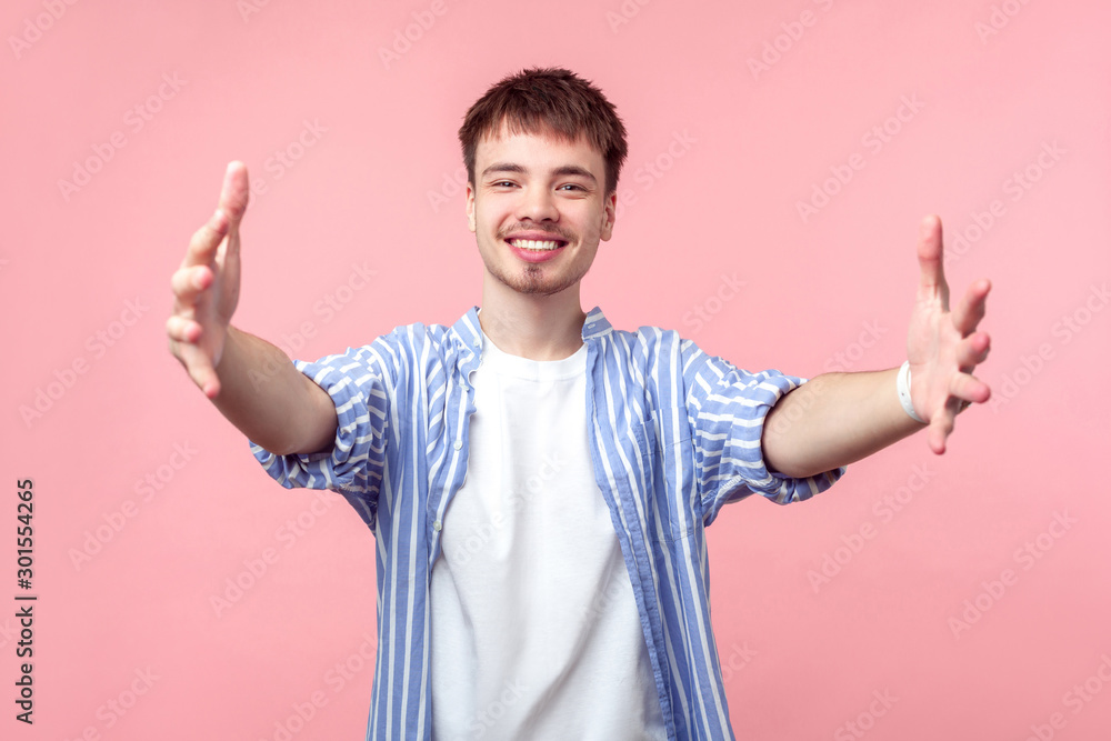 Free hugs. Come here. Portrait of friendly kind brown-haired man with small beard and mustache in casual striped shirt stretching hands to embrace. indoor studio shot isolated on pink background Free hugs. Come here. Portrait of friendly kind brown-haired man with small beard and mustache in casual striped shirt stretching hands to embrace. indoor studio shot isolated on pink background