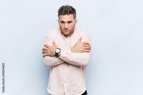 Young handsome cool man going cold due to low temperature or a sickness.