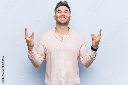 Young handsome cool man showing rock gesture with fingers