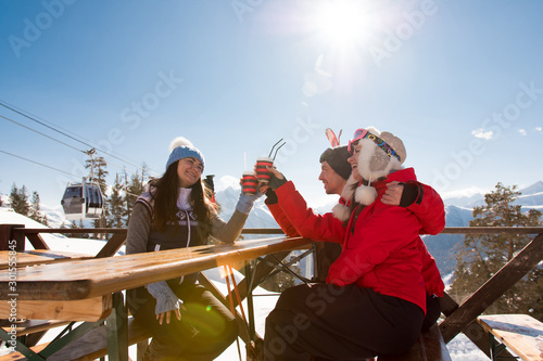 Group Of Friends Enjoying Hot Mulled Wine In Cafe At Ski Resort. photo