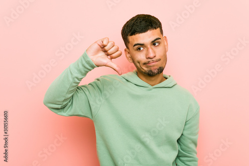 Young hispanic sport man showing a dislike gesture, thumbs down. Disagreement concept. © Asier