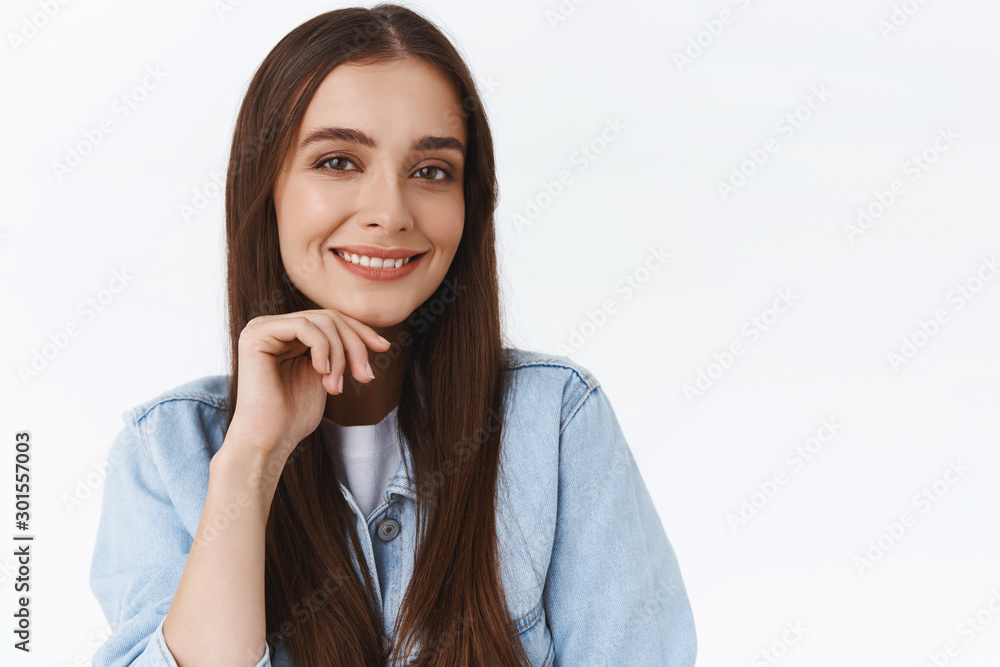 Close-up sassy good-looking confident young feminine woman in denim jacket, with long healthy hair, touching chin and smiling self-assured, standing pleased and upbeat over white background Close-up sassy good-looking confident young feminine woman in denim jacket, with long healthy hair, touching chin and smiling self-assured, standing pleased and upbeat over white background