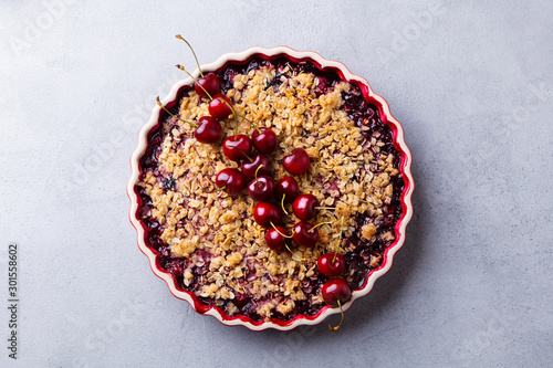 Cherry, red berry crumble in baking dish. Grey stone background. Top view. photo