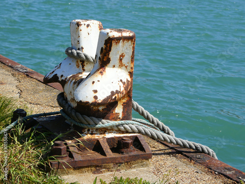 Lines from boats hang off of a rusted mooring bollard in Shoreham Harbour