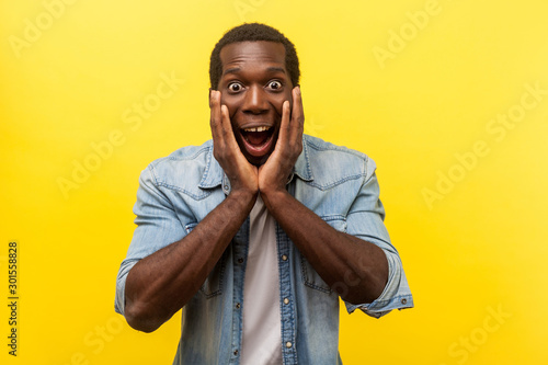 Fényképezés Oh my god, wow! Portrait of stunned shocked man in denim shirt holding hands on face and looking with big amazed eyes, surprised by unbelievable news