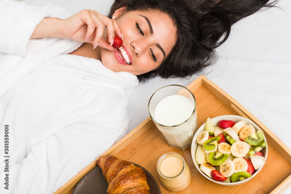 Young hispanic woman having breakfast on the bed Young hispanic woman having breakfast on the bed
