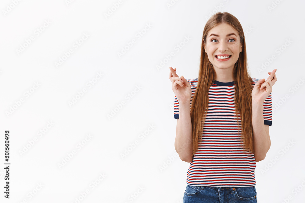 Hopeful, cheerful cute fair-haired woman with long hair in striped t-shirt anticipating important news, believe dreams come true, have faith positive results, smiling happily, cross fingers good luck Hopeful, cheerful cute fair-haired woman with long hair in striped t-shirt anticipating important news, believe dreams come true, have faith positive results, smiling happily, cross fingers good luck