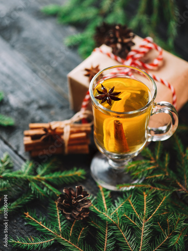 Christmas drink grog with lemon, cinnamon, wine on wooden table with gift boxes for holiday