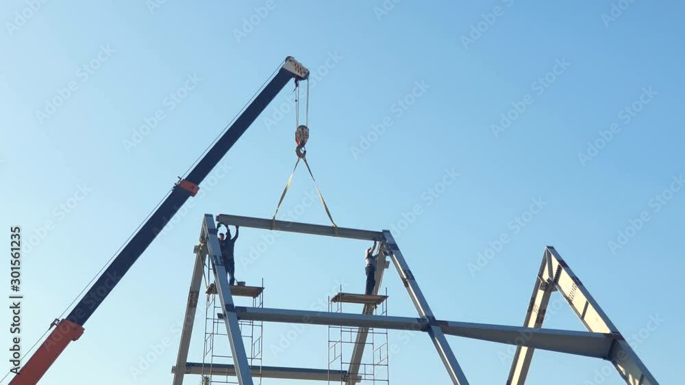 Installation of a roof and a framework from a metal construction. Workers mount the roof. Installation of a roof and a framework from a metal construction. Workers mount the roof.