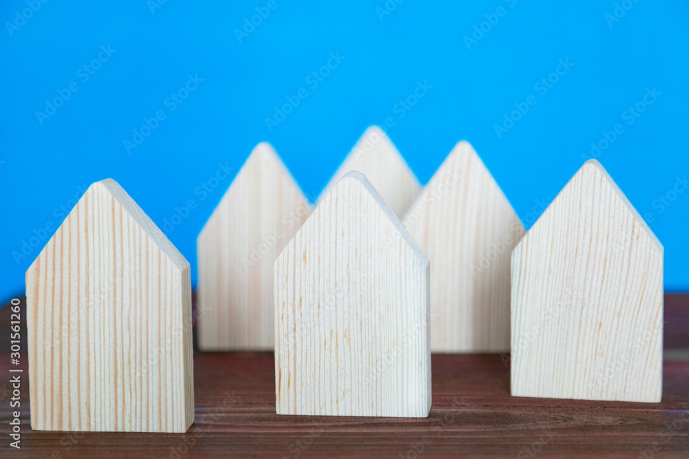 Model of a small village of several houses. Six symbolic houses made of light wood on a blue background. Model of a small village of several houses. Six symbolic houses made of light wood on a blue background.